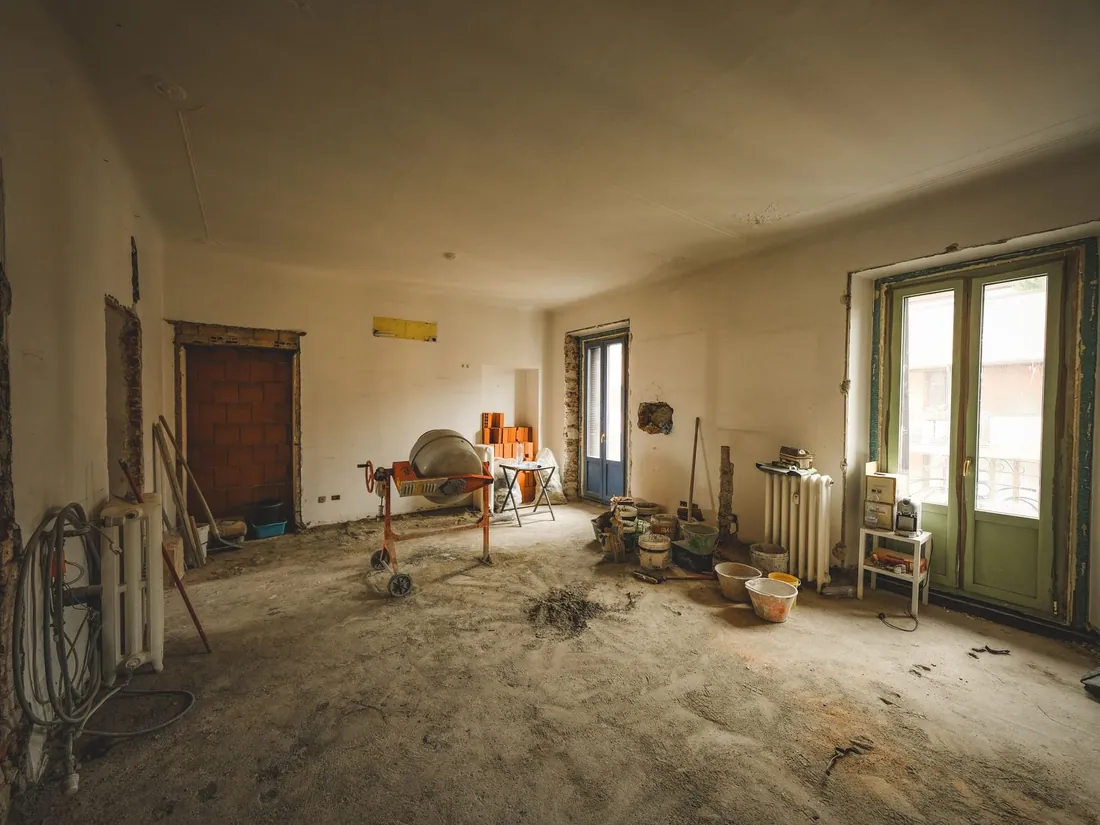Telpa pirms rekonstrukcijas — noplēsta apdare, atsegtas sienas un vecs radiators